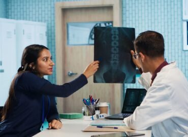 Indian general practitioner and nurse examine hospital records and x ray tests, finding diagnosis for a patient. Medical staff reviewing scans and doing healthcare reports with expertise. Camera A.
